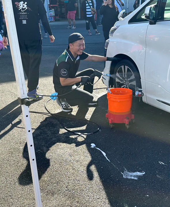 笑顔で洗車サービスを行うPlusスタッフ